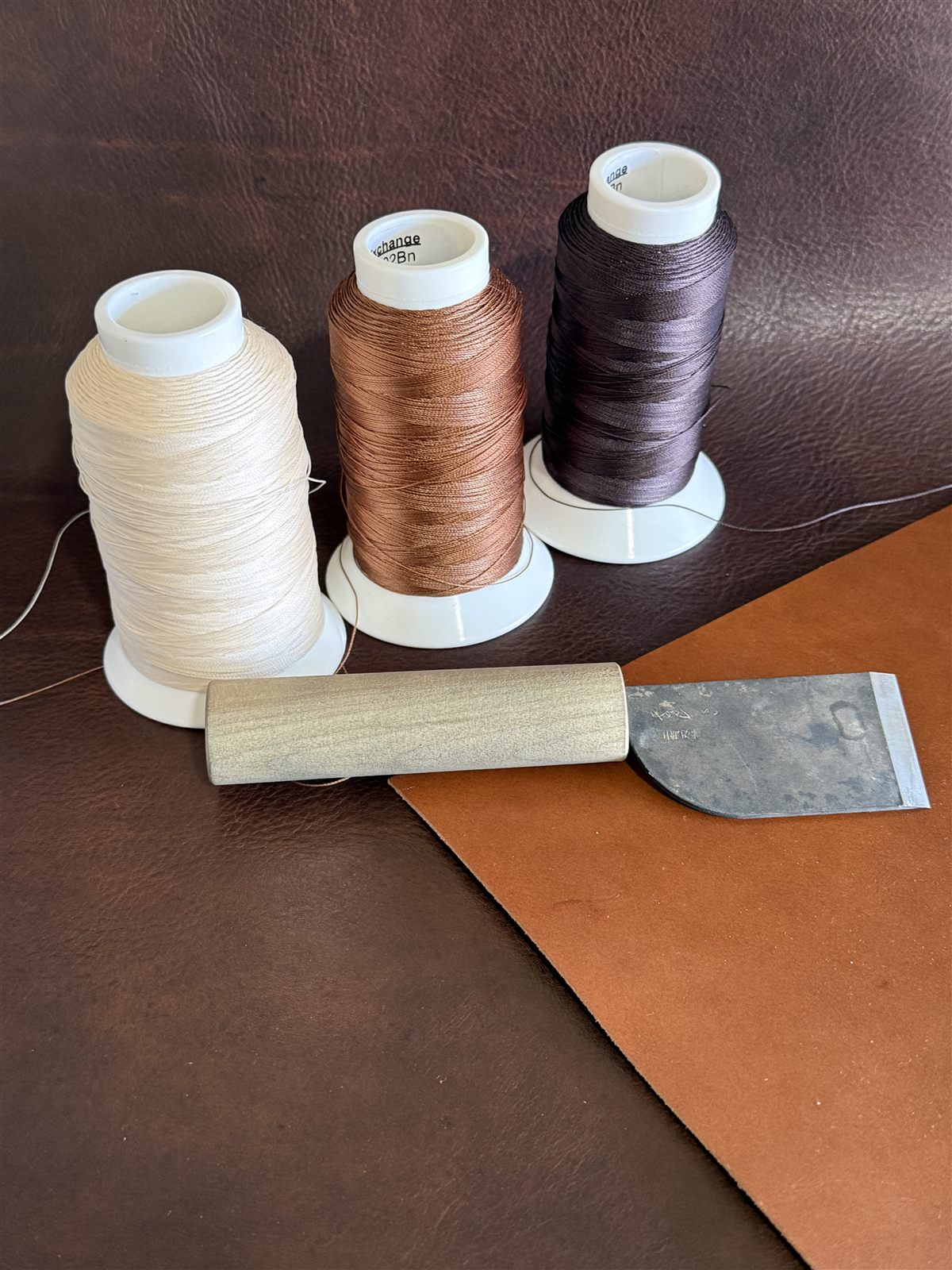 Leather, cutting knife, and thread spools used to hand-stitch each Pelli headcover
